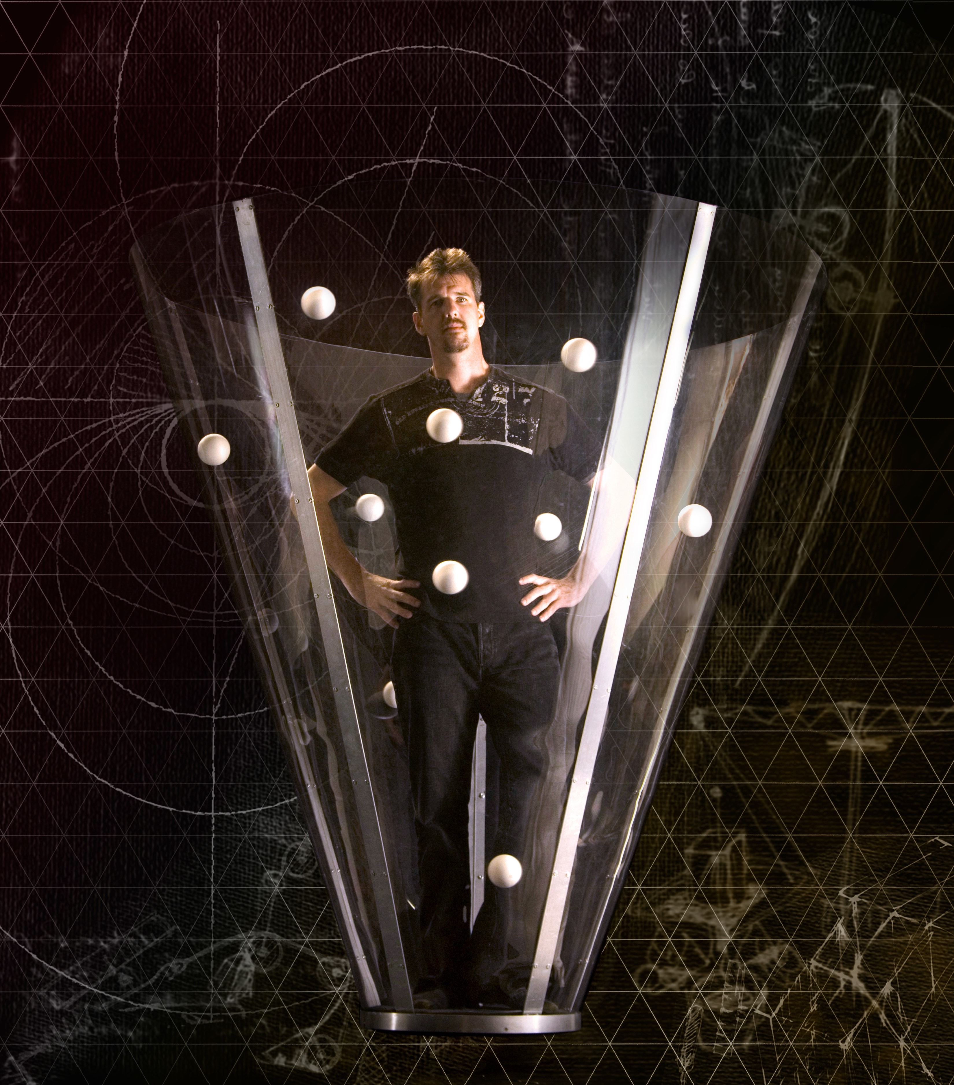 Greg Kennedy standing in a clear cone with juggling balls circling him